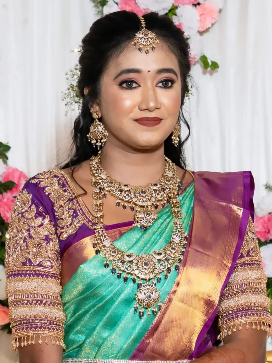 Bride in a green and purple silk saree with bridal makeup and gold jewellery