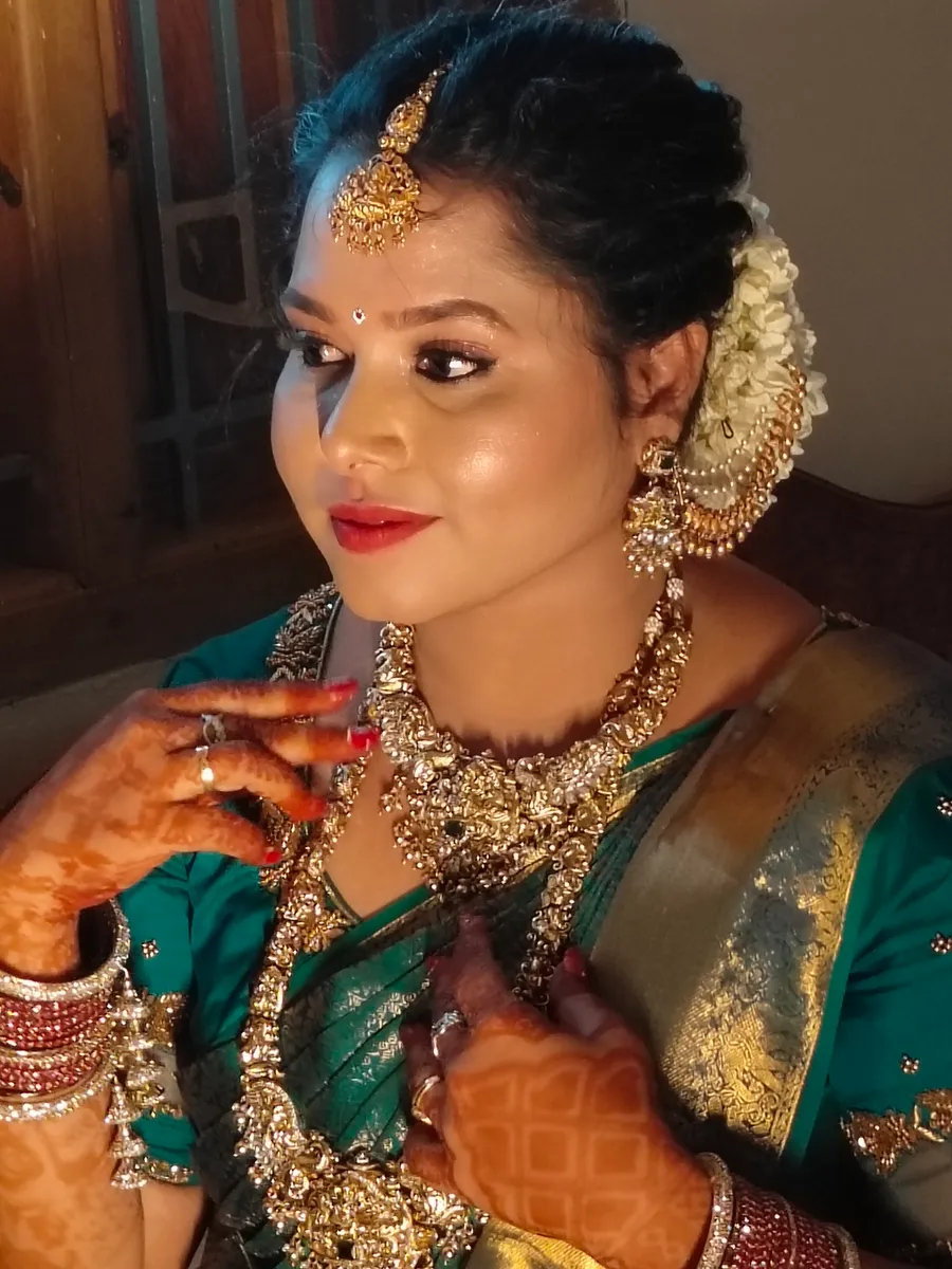 Bride in a green silk saree with bridal makeup and jasmine hair flowers