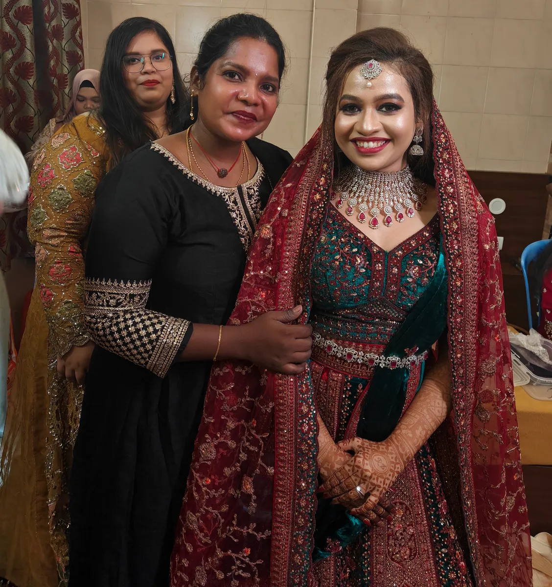 Bride in dark reception attire posing with family members