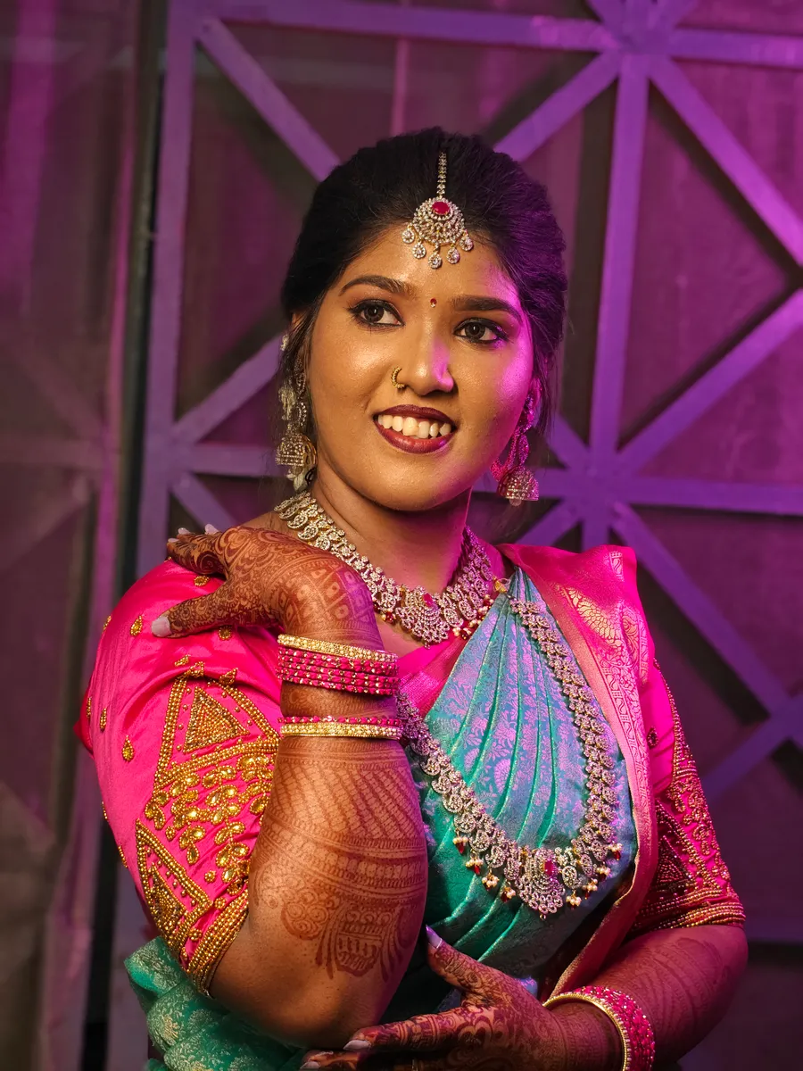 Bride in a pink and blue silk saree with wedding makeup and gold jewellery