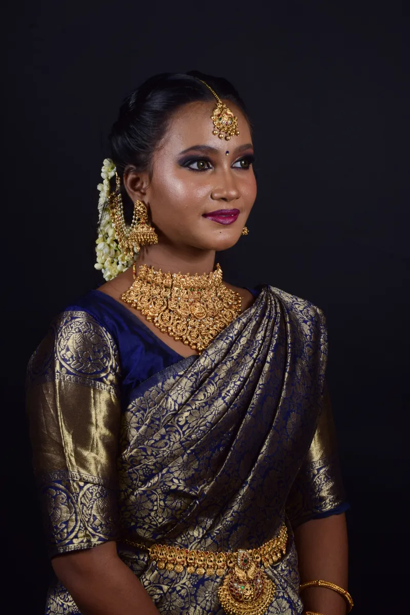 Bridal portrait in a navy silk saree with gold jewellery and wedding makeup