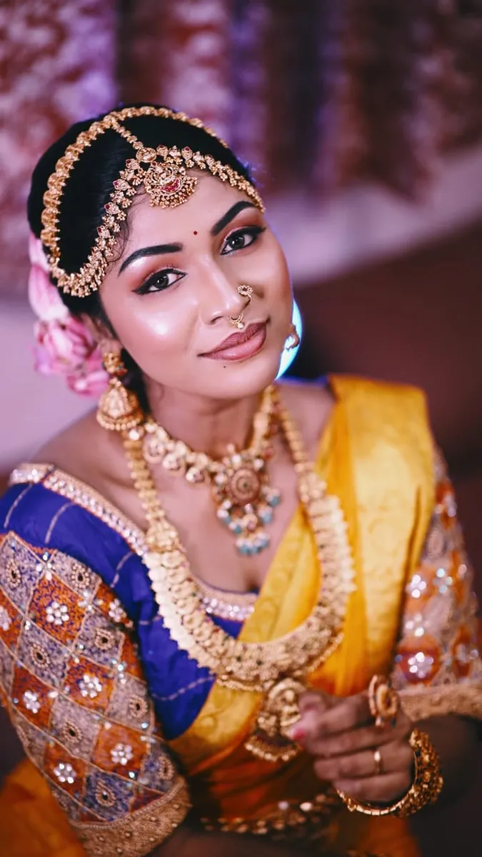 Bride in a blue and yellow silk saree with eye makeup and bridal jewellery